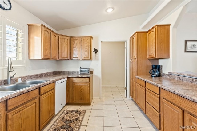 kitchen featuring light tile patterned floors, dishwasher, vaulted ceiling, light countertops, and a sink