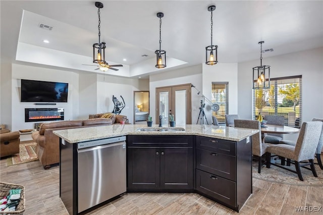 kitchen featuring visible vents, a kitchen island, open floor plan, stainless steel dishwasher, and a sink