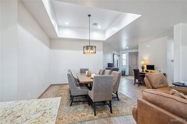 dining room with recessed lighting, wood finished floors, visible vents, baseboards, and a raised ceiling