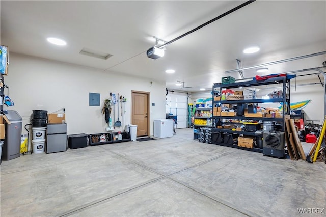 garage featuring electric panel, freestanding refrigerator, and a garage door opener