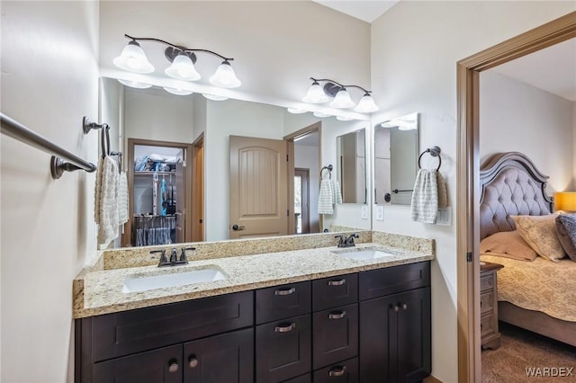 ensuite bathroom featuring connected bathroom, a walk in closet, a sink, and double vanity