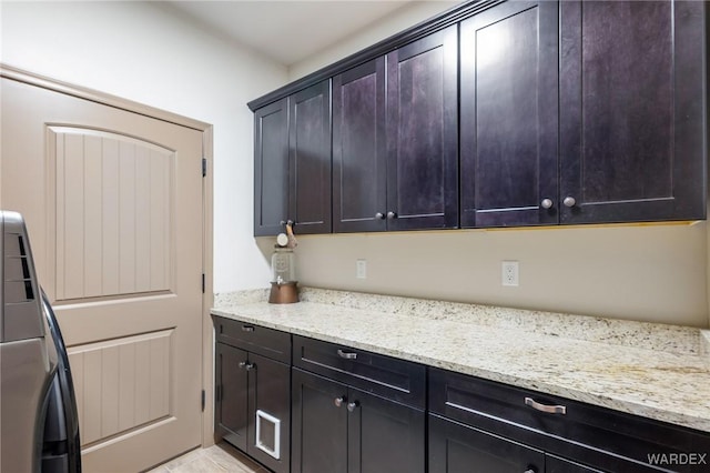 kitchen featuring light stone counters and washer / dryer