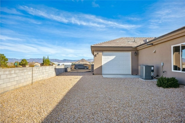 view of side of property with cooling unit, a fenced backyard, a mountain view, and stucco siding