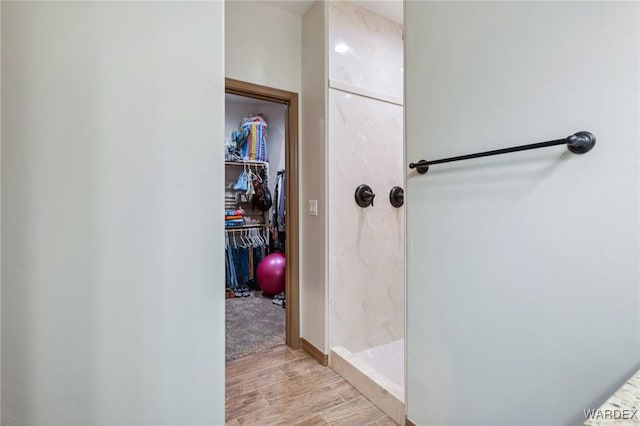 full bath featuring a walk in closet, wood tiled floor, and a walk in shower