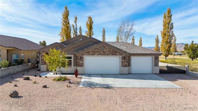 single story home with a garage, fence, driveway, stone siding, and a tiled roof