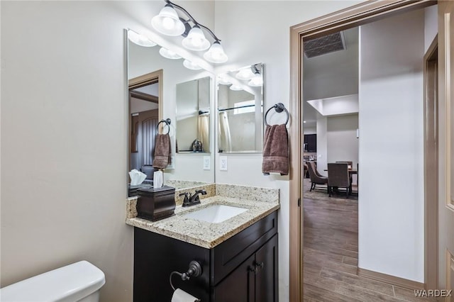 bathroom with visible vents, vanity, toilet, and wood finished floors