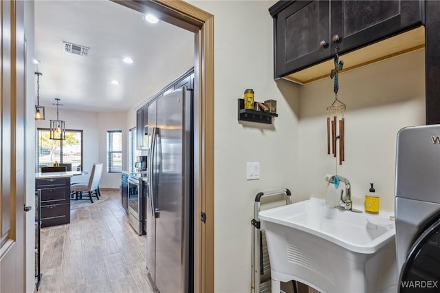 kitchen with light wood finished floors, light countertops, appliances with stainless steel finishes, and visible vents