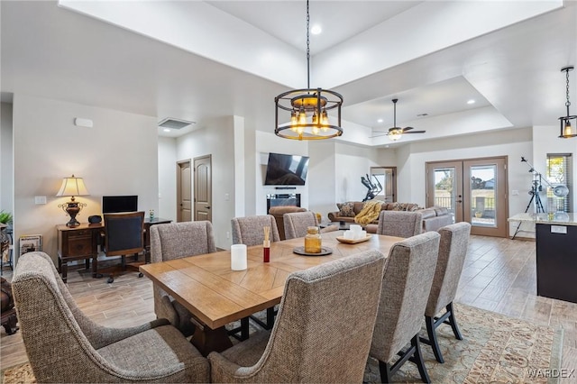 dining room with light wood-style floors, recessed lighting, a raised ceiling, and french doors