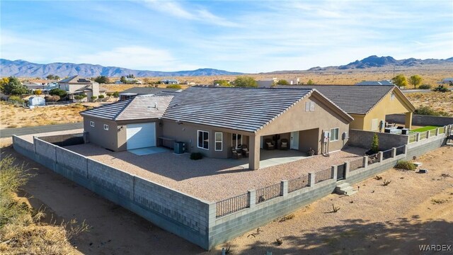 exterior space featuring a patio area, a fenced backyard, a mountain view, and a tiled roof