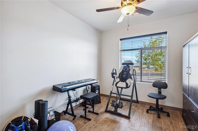 exercise area featuring a ceiling fan, baseboards, and wood finished floors