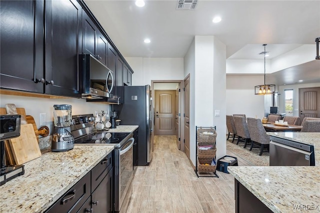 kitchen featuring hanging light fixtures, light stone countertops, visible vents, and stainless steel appliances