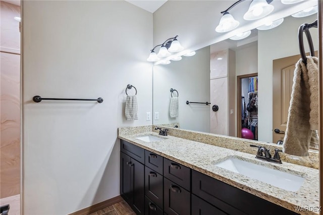 full bath featuring double vanity, wood finished floors, a sink, and baseboards