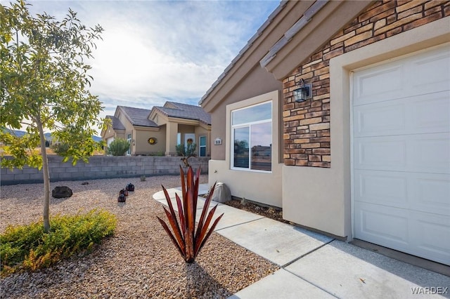 exterior space with a garage, stone siding, and stucco siding