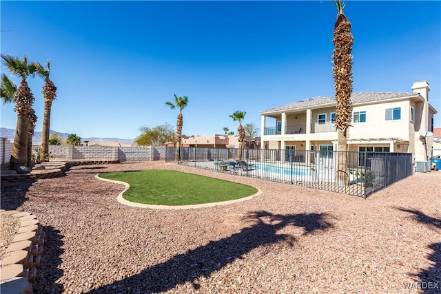 rear view of property featuring a fenced backyard, central air condition unit, a fenced in pool, stucco siding, and a patio area