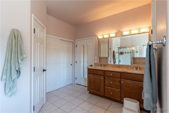 full bath featuring double vanity, a stall shower, tile patterned flooring, and a sink