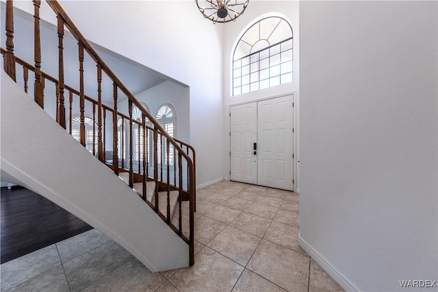 tiled entryway with a high ceiling, stairs, and baseboards