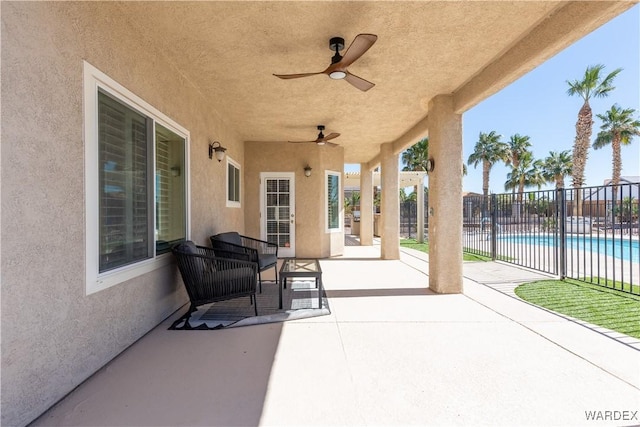 view of patio featuring ceiling fan, fence, and a fenced in pool