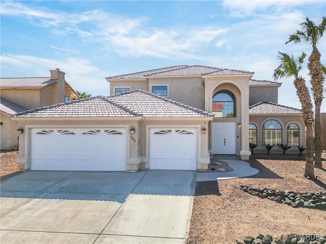 mediterranean / spanish house with concrete driveway, a tile roof, an attached garage, and stucco siding