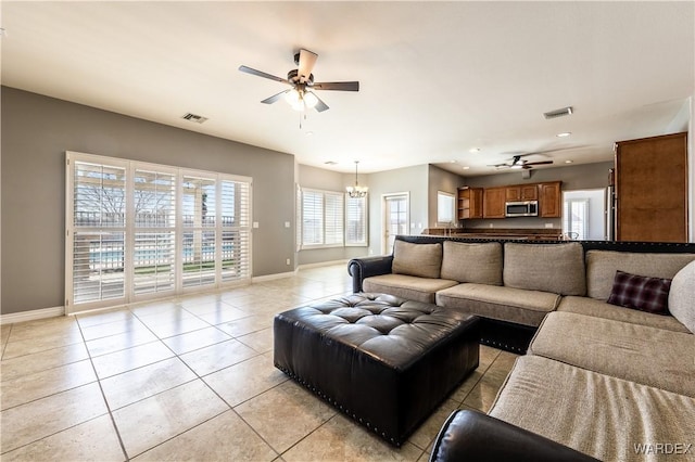 living area with ceiling fan with notable chandelier, light tile patterned floors, visible vents, and baseboards