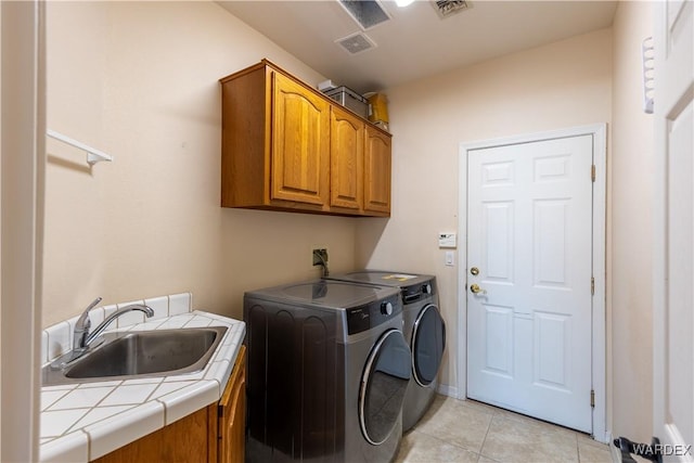 clothes washing area with cabinet space, visible vents, a sink, and washing machine and clothes dryer