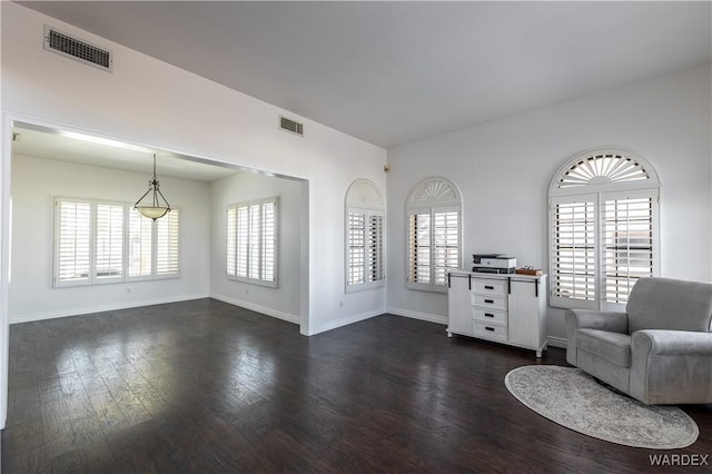 unfurnished room featuring a healthy amount of sunlight, dark wood-style floors, baseboards, and visible vents