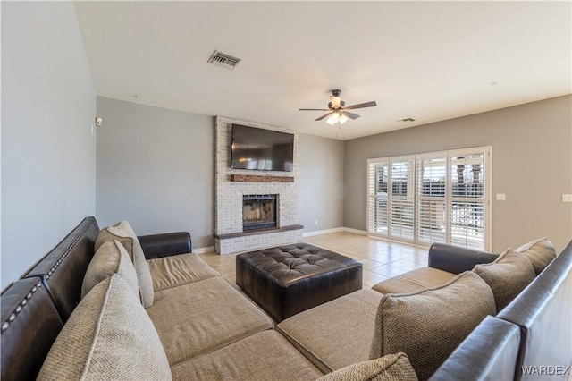 living area with light tile patterned floors, visible vents, a ceiling fan, a brick fireplace, and baseboards