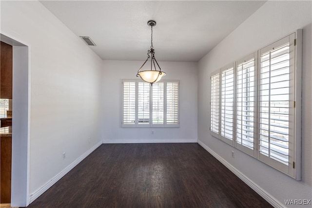 empty room featuring wood finished floors, visible vents, and baseboards