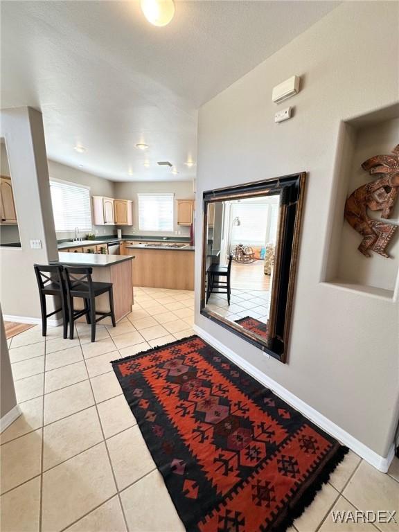 interior space featuring light tile patterned floors, baseboards, and a sink