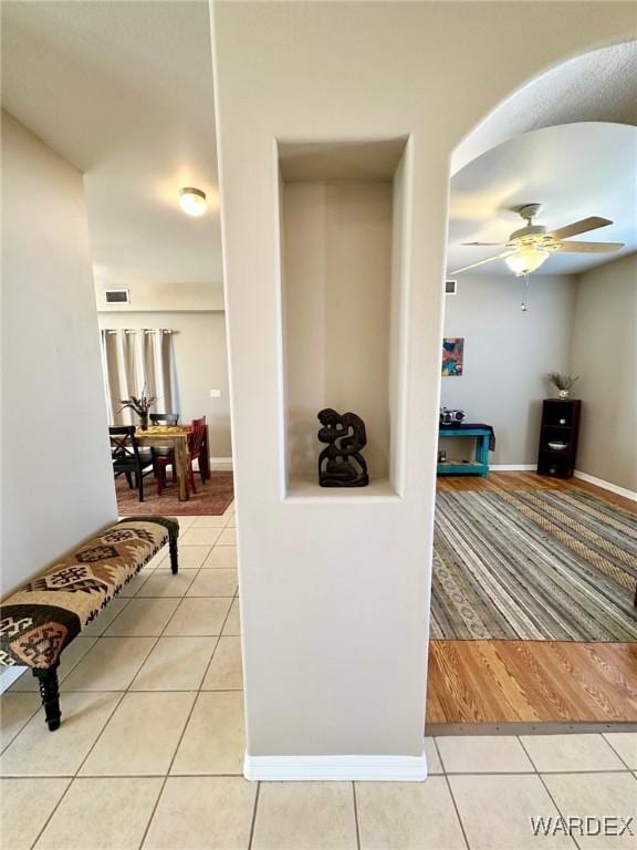 hall with light tile patterned flooring, visible vents, and baseboards