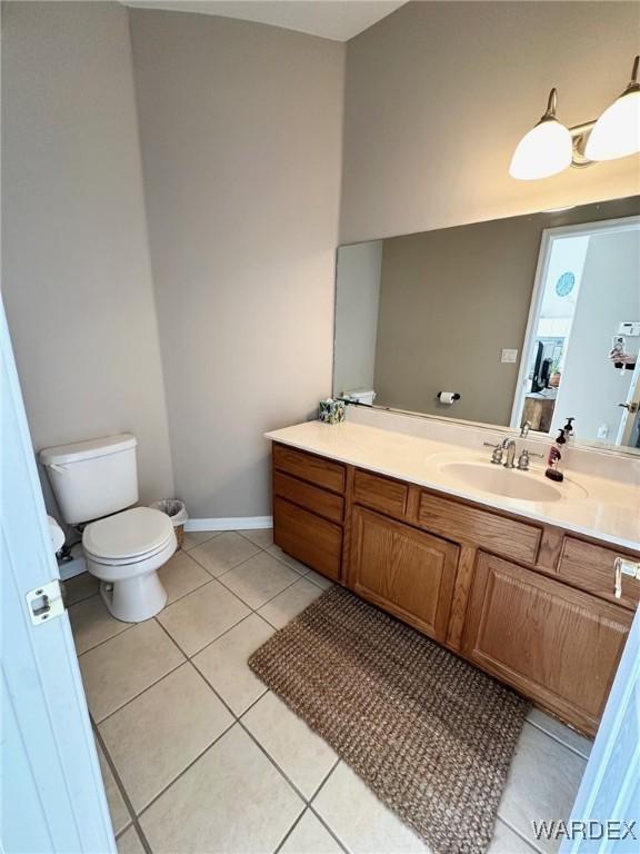 bathroom with tile patterned flooring, baseboards, vanity, and toilet