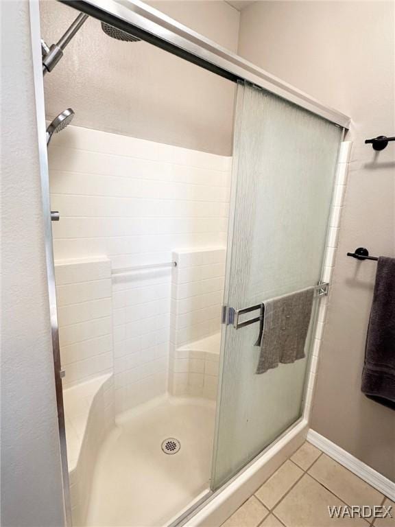bathroom featuring tile patterned flooring, a stall shower, and baseboards