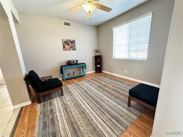 living area featuring visible vents, ceiling fan, baseboards, and wood finished floors