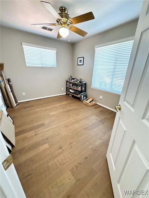 interior space featuring ceiling fan, wood finished floors, visible vents, and baseboards