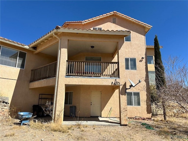 back of property with stucco siding, a patio, and a balcony