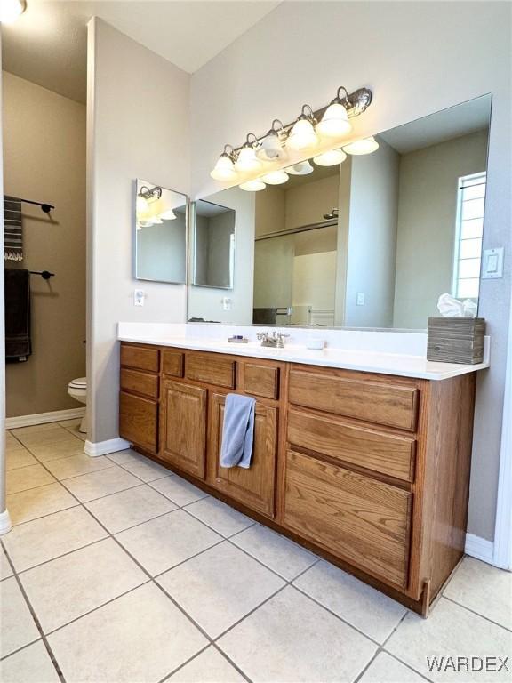 full bathroom with baseboards, vanity, toilet, and tile patterned floors