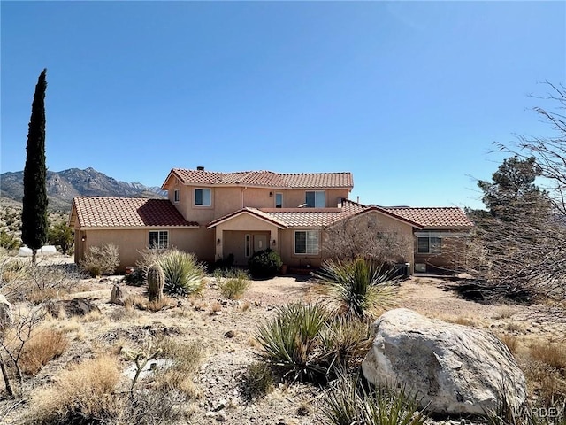 back of property featuring stucco siding, a tiled roof, and a mountain view
