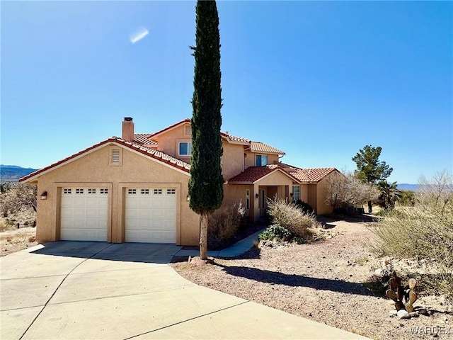 mediterranean / spanish-style home with a garage, concrete driveway, a chimney, a tiled roof, and stucco siding