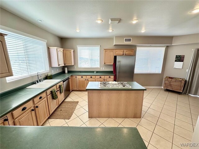 kitchen with light tile patterned floors, light brown cabinets, stainless steel appliances, a sink, and visible vents