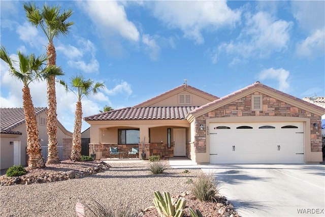 mediterranean / spanish-style home with stucco siding, stone siding, covered porch, concrete driveway, and a garage