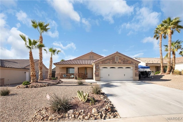 view of front of house featuring concrete driveway, a tile roof, stucco siding, a garage, and stone siding