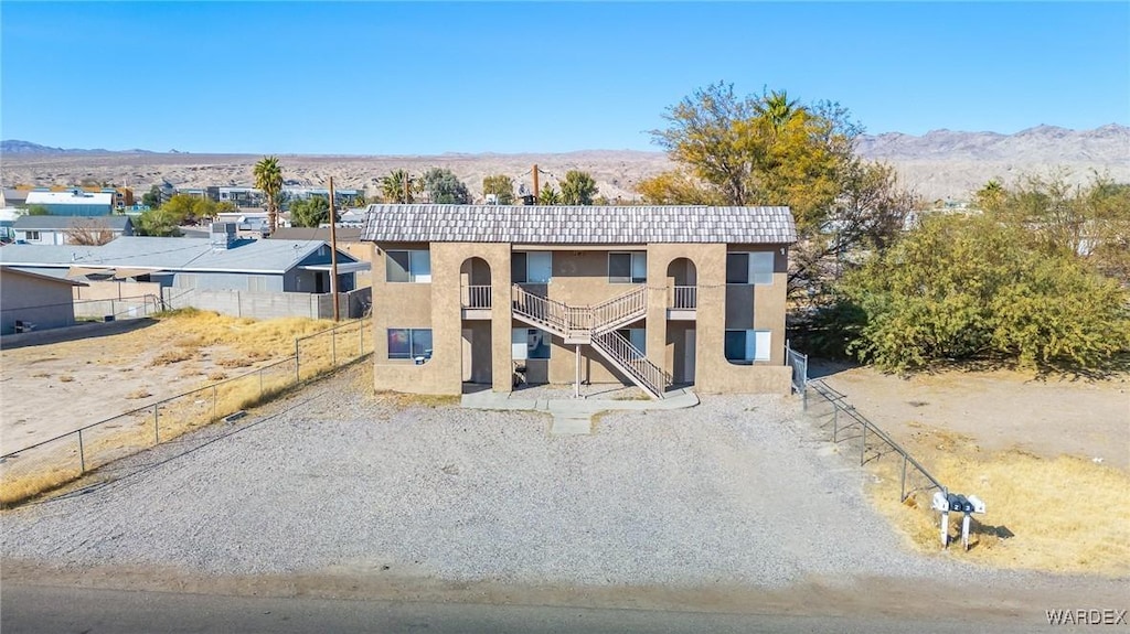 view of outbuilding with stairs, a mountain view, and fence