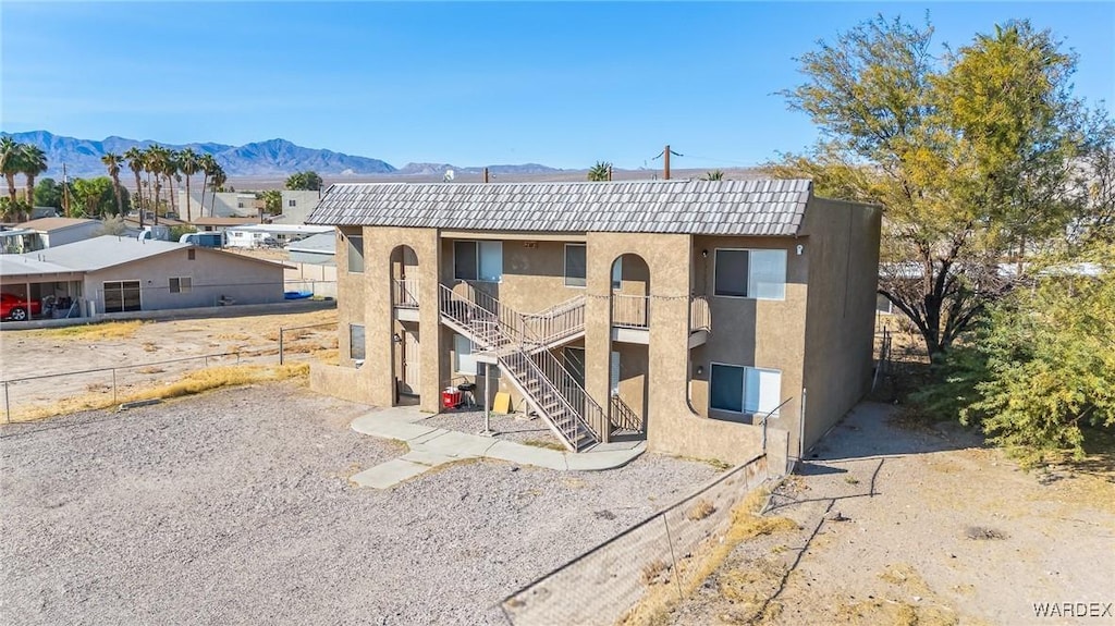 view of front of home with a tile roof, a mountain view, stairway, and stucco siding