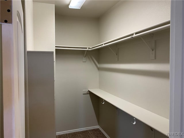 walk in closet featuring dark colored carpet