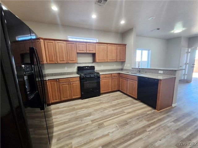 kitchen featuring brown cabinets, light countertops, visible vents, a sink, and black appliances