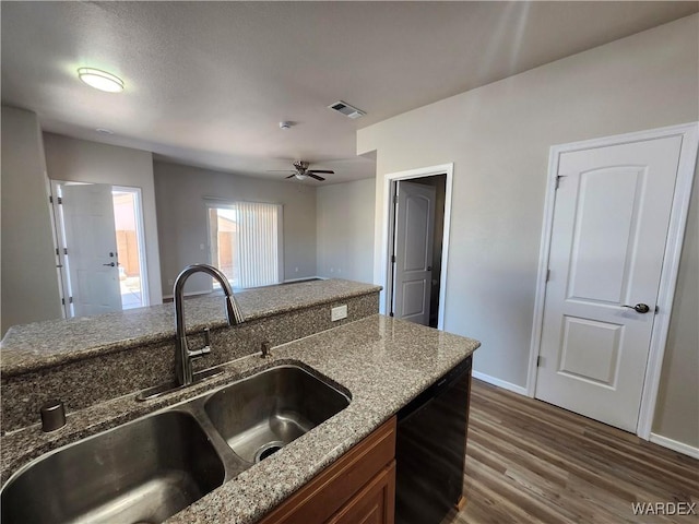 kitchen with black dishwasher, dark wood-style floors, brown cabinets, stone counters, and a sink