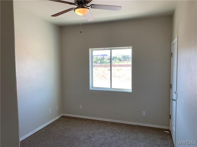 carpeted spare room featuring baseboards and a ceiling fan