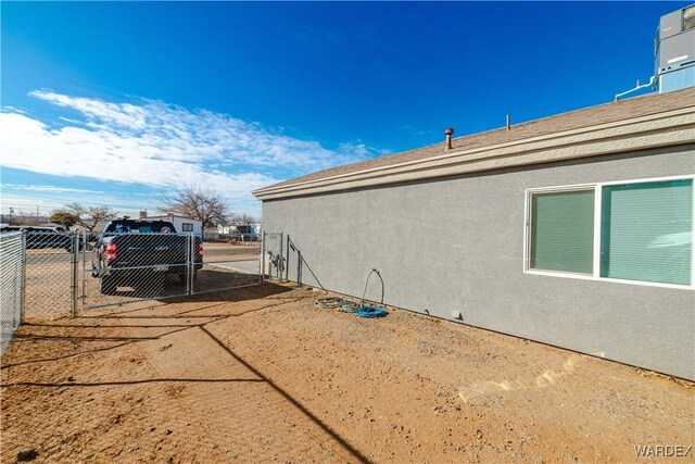 view of side of property with fence, a gate, and stucco siding