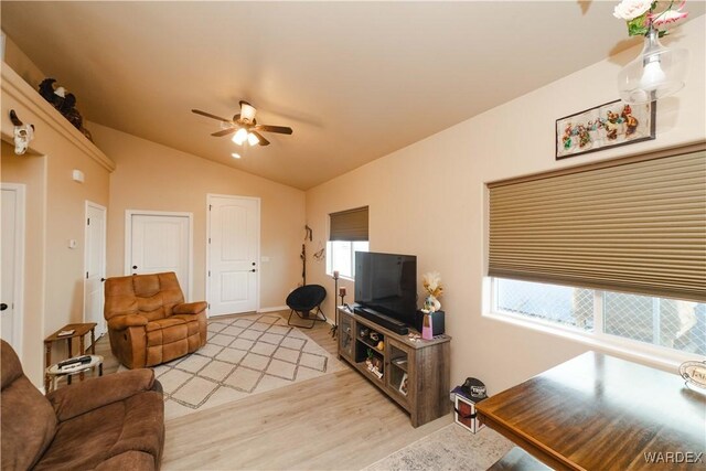 living area featuring light wood-type flooring, vaulted ceiling, and a ceiling fan