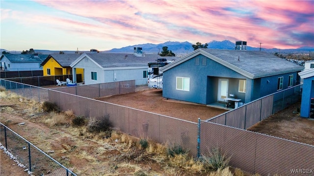 back of house featuring a fenced backyard, a mountain view, and stucco siding