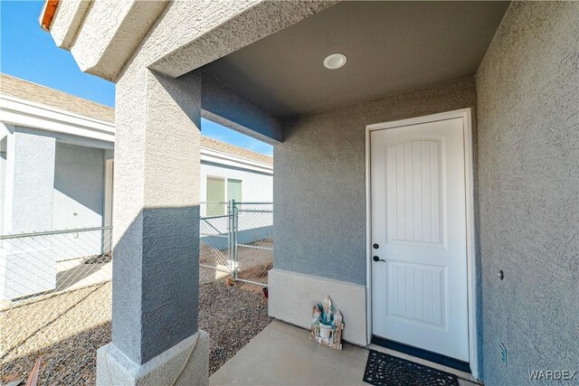 property entrance featuring fence and stucco siding